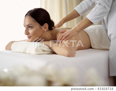 Pretty brunette woman enjoying procedure of back massage in spa salon. Beauty concept Pretty brunette woman enjoying procedure of back massage in spa salon. Beauty concept 61928718