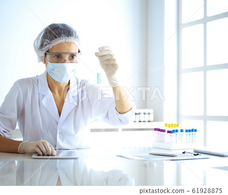 Professional female scientist in protective eyeglasses researching tube with reagents in laboratory. Concepts of medicine and research 61928875