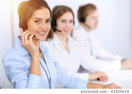 Call center. Focus on beautiful business woman using headset in sunny office 61930019