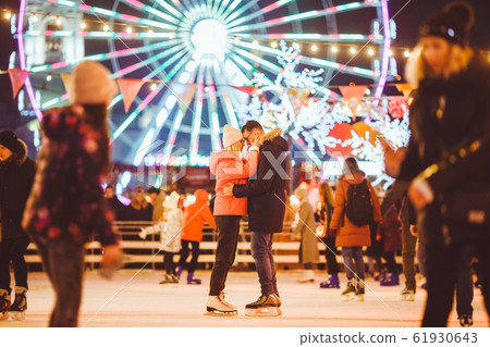 Couple in Love. Romantic Characters for Feast of Saint Valentine. True love. Happy Couple Having Fun at city ice rink in the evening. Happy romantic young couple enjoying together in skating-rink 61930643