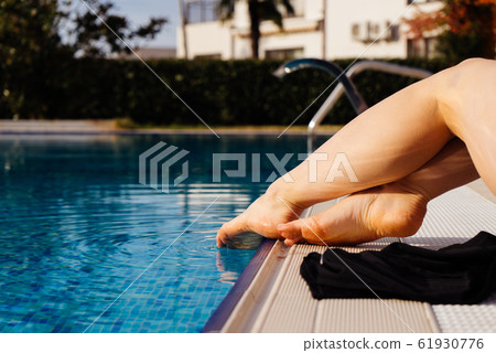 beautiful female legs touch the water in the pool beautiful female legs touch the water in the pool 61930776