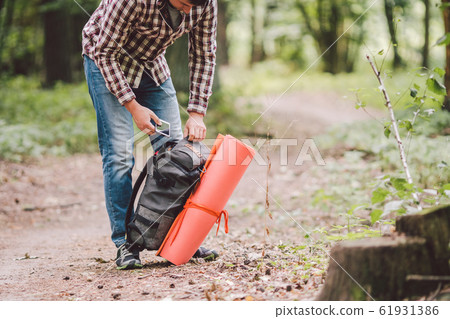 Hiker holding his camping backpack. traveler opening backpack while traveling in beautiful wood. Theme hiking and travel. Man traveling in forest with backpack. Active healthy man hiking in forest 61931386