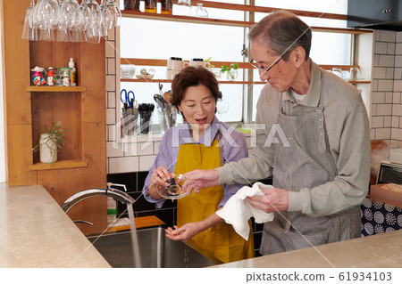Senior couple washing together in the kitchen Senior couple washing together in the kitchen 61934103