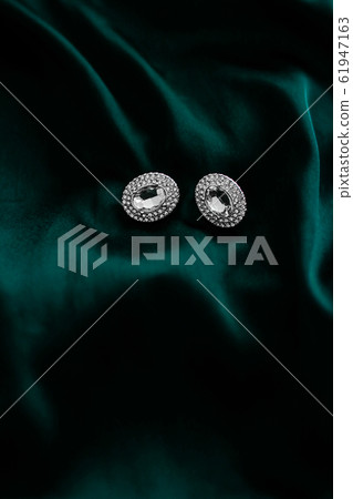 Luxury diamond earrings on dark emerald green 61947163