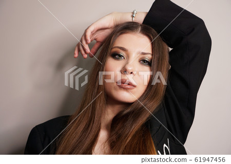 Beautiful young white girl close-up in a black jacket on a gray background 61947456