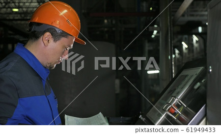 Operator monitors control panel of production line. Manufacture of plastic water pipes factory. Process of making plastic tubes on the machine tool with the use of water and air pressure. 61949433