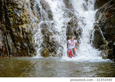 Girl traveling waterfall on holiday. The girl who is enjoying playing the waterfall happily. 61950490