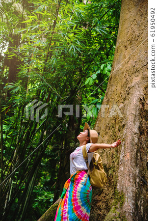 A girl with a backpack is embracing a big tree. enjoying  travel nature 61950492