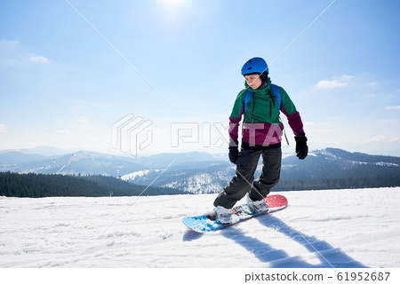 Young female snowboarder riding snowboard on sunny winter day. Winter sports and recreation. Young female snowboarder riding snowboard on sunny winter day. Winter sports and recreation. 61952687