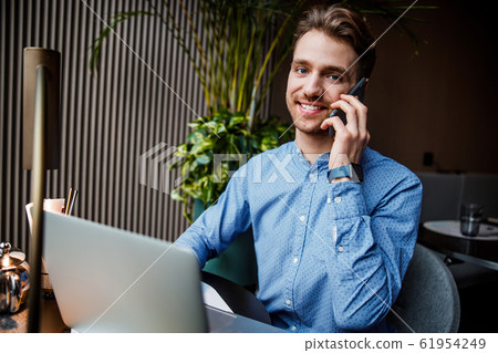 Handsome man in blue shirt working on laptop computer in cafe 61954249