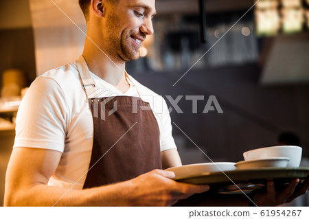 Caucasian happy waiter waiting for order near the kitchen 61954267