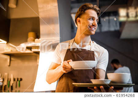 Caucasian nice waiter waiting for order near the kitchen Caucasian nice waiter waiting for order near the kitchen 61954268