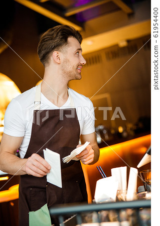 Attentive young male cafe worker doing his duties at work place 61954400