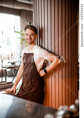 Caucasian attractive young waiter waiting for clients in beautiful cafe 61954434
