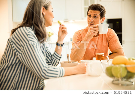 Smiling beautiful lady looking at man while having breakfast at home 61954851