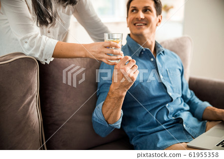 Smiling man taking glass of water from his wife Smiling man taking glass of water from his wife 61955358