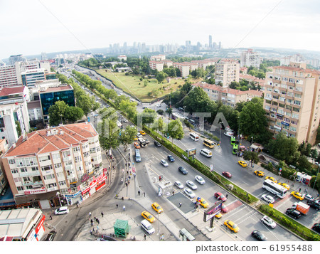 從高高的汽車和行人橫過馬路，遠處可見棕色屋頂的房屋和高層建築的伊斯坦布爾城市景觀 61955488