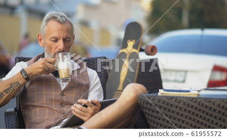 European man with longboard reads the news in a street cafe 61955572