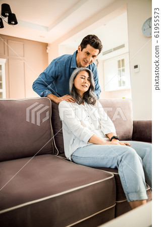 Smiling husband massaging wife shoulders at home 61955573
