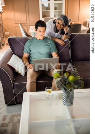 Smiling mature man holding laptop at home Smiling mature man holding laptop at home 61955629