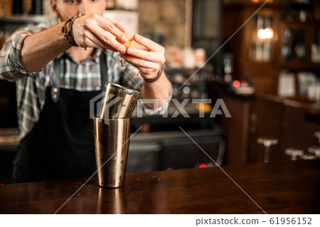 Bartender in apron using a cocktail shaker Bartender in apron using a cocktail shaker 61956152