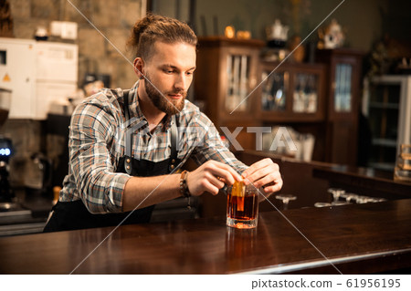 Bearded young barman is completing cocktail making Bearded young barman is completing cocktail making 61956195