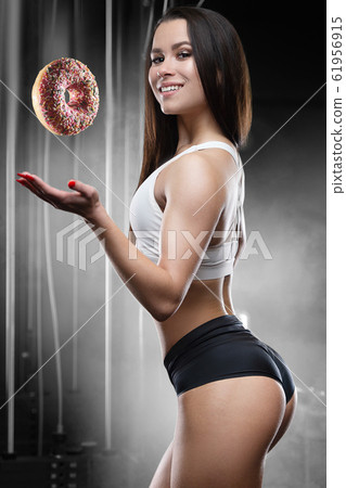 Fitness woman with donut at workout in the gym Fitness woman with donut at workout in the gym 61956915