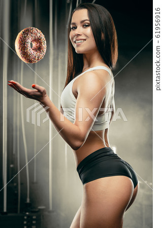 Fitness woman with donut at workout in the gym 61956916