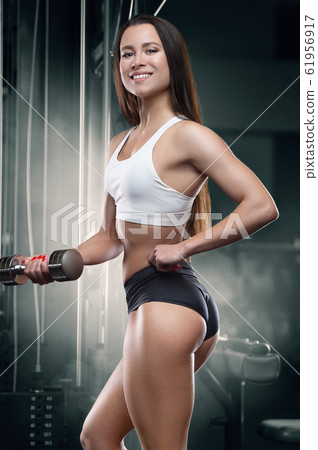 Fitness woman pumping up arm muscles in the gym Fitness woman pumping up arm muscles in the gym 61956917