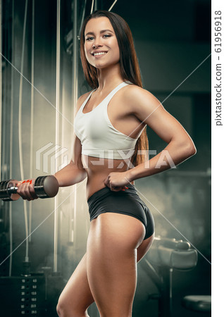 Fitness woman pumping up arm muscles in the gym Fitness woman pumping up arm muscles in the gym 61956918