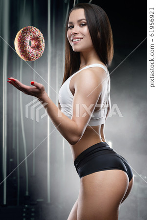 Fitness woman with donut at workout in the gym Fitness woman with donut at workout in the gym 61956921