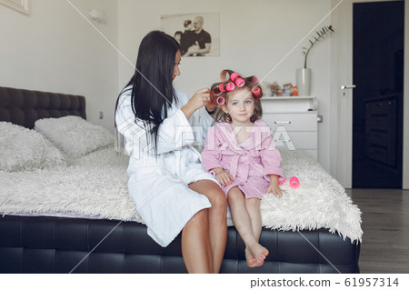 Mom and daughter at home with curlers on their heads 61957314