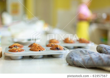 Confectioner took out freshly baked muffins in a Confectioner took out freshly baked muffins in a 61957567