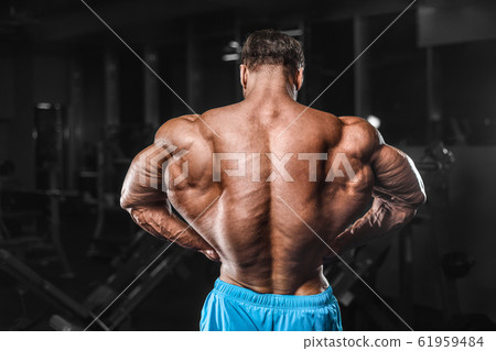 Bodybuilder strong man pumping up biceps muscles 61959484
