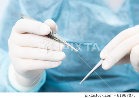 Surgeon holding a surgical needle holder with silk Surgeon holding a surgical needle holder with silk 61967873