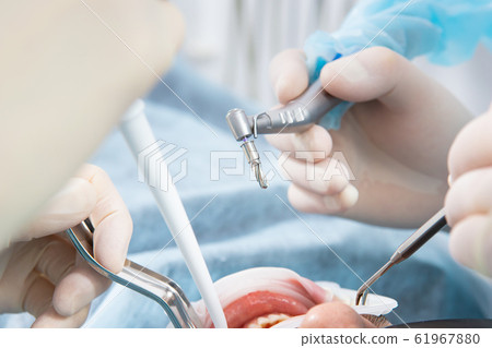 Dentist's hands in sterile gloves close-up, with 61967880