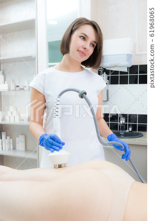 The cosmetologist reduces cellulite on the The cosmetologist reduces cellulite on the 61968065