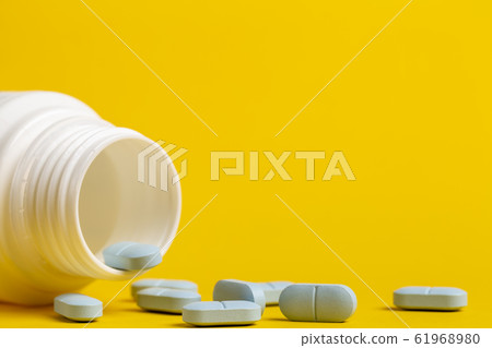 Medicine bottle and blue pills scattered around Medicine bottle and blue pills scattered around 61968980