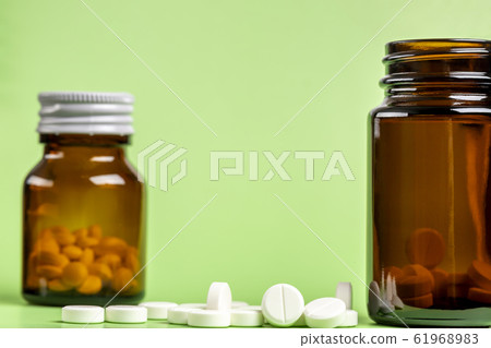 Glass and plastic drug bottles with white pills inside Glass and plastic drug bottles with white pills inside 61968983