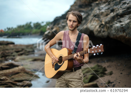 Romantic young man with a guitar on the beach Romantic young man with a guitar on the beach 61970294