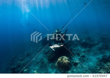 Young woman free diver glides with fins near underwater temple. Freediving in blue ocean 61970947