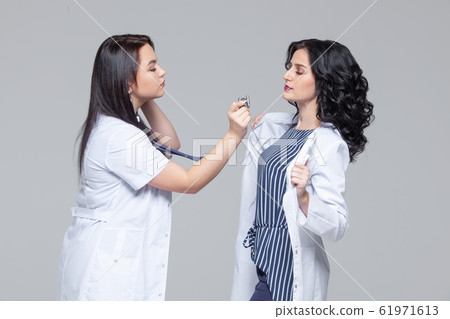 Female doctor examining another woman with stethoscope 61971613