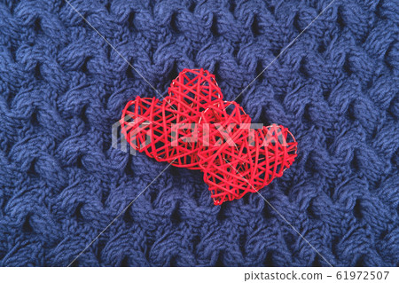 Two red hearts on the blue knit background. 61972507