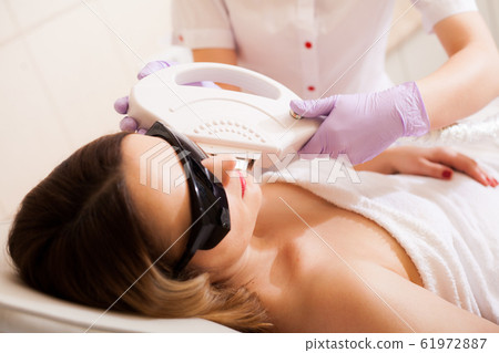 Woman receiving laser epilation treatment on her face Woman receiving laser epilation treatment on her face 61972887