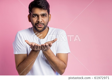 Portrait of handsome Indian guy standing on pink 61972971