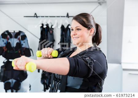 Big woman working on her fitness in ems gym with weights 61973214