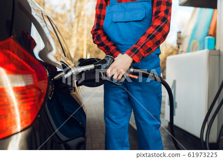 Male worker in uniform fuels car on gas station 61973225