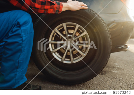 Male worker in uniform fix problem with tire 61973243
