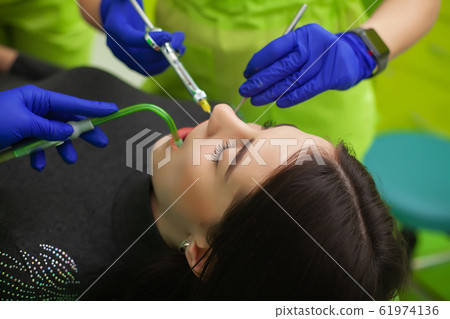 The dentist are treating teeth to client in dental office 61974136