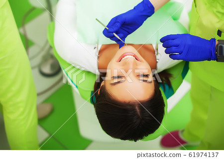 The dentist are treating teeth to client in dental office 61974137